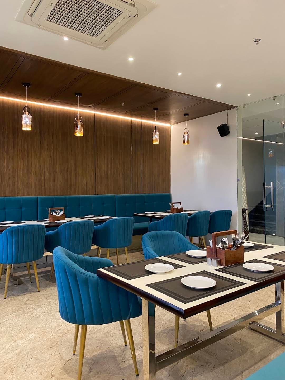 Elegant restaurant dining area with blue velvet chairs at Sujata Hotel